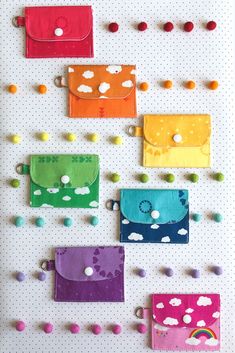 several colorful purses are hanging on a pegboard with buttons and pins attached to them