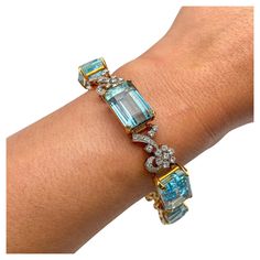 "This vintage bracelet showcases a central emerald-cut aquamarine weighing 0.80 carats, surrounded by accents of 2.00 carats of diamonds, all set in platinum and 18-karat gold. The aquamarines exhibit a captivating aqua blue color, adding to the bracelet's elegance and charm." Natural No Heat aquamarins