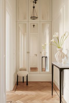 a room that has some white flowers in vases on the table and a chair next to it