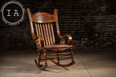 a wooden rocking chair sitting in front of a brick wall