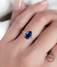 a woman's hand wearing a ring with a blue gemstone and diamond accents