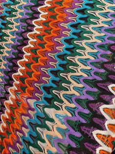 a multicolored crocheted blanket is laying on the floor