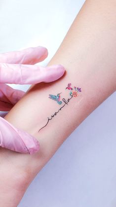 a woman's arm with the word love written on it and flowers painted on it