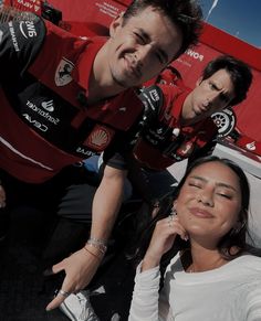 two people are taking a selfie in front of a red wall with other people