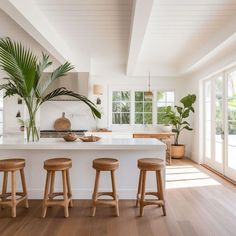 a kitchen with white counter tops and wooden stools next to an island in the middle