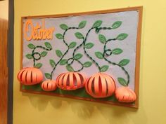 paper lanterns are hanging on the wall in front of a bulletin board with leaves and letters