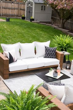 a white couch sitting on top of a wooden table next to a lush green field