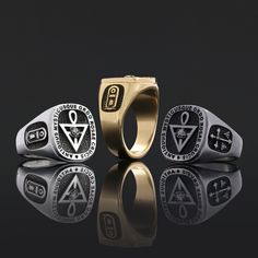 three rings with symbols on them sitting in front of a black background, one is gold and the other is silver