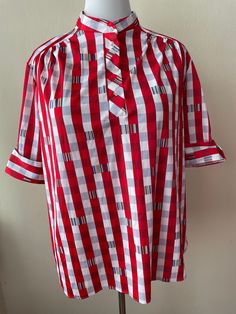 "Vintage 80s red and white striped short sleeve shirt, mock neck style. Blue and yellow geometric pattern. Four buttons at chest. 100% polyester, cuffed sleeve. Marked size 44, best for XL/2XL.  Please ask questions!  Measurements (laid flat):  Tag Size: 44 Length: 25.5\" Pit to Pit: 24\"x2 Waist: 25\"x2 Condition: Excellent vintage condition, no issues noted.  The vintage pieces I sell have all led a previous life and may tell their stories through minor imperfections. I'll do my best to indicate overall condition, but please refer to the pictures. Your purchase continues the life of this garment...what stories will you tell while wearing it?  Please note there may be a slight difference in color when comparing the actual garment to the monitor image. (0441)" Red Collared Blouse With Relaxed Fit, Red Short Sleeve Cotton Blouse, Retro Red Shirt For Spring, Classic Red Top With Striped Collar, Retro Red Summer Shirt, Red Top With Striped Collar For Spring, Red Retro Summer Blouse, Red Spring Top With Striped Collar, Retro Short Sleeve Plaid Blouse