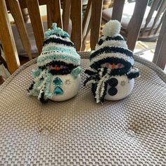 two knitted snowmen sitting on top of a wooden chair