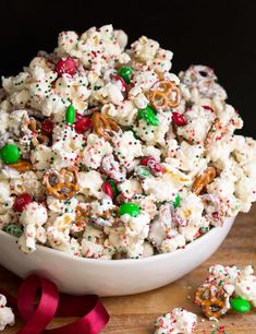 a bowl filled with white chocolate and sprinkles on top of a wooden table