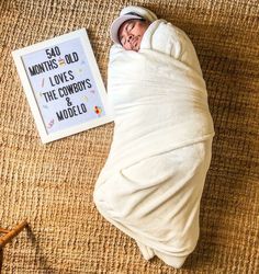 a baby wrapped in a blanket next to a book