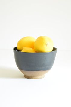 a bowl filled with lemons on top of a white table