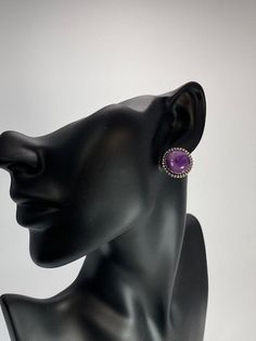 Just a perfect size for a button earrings and a perfect color for the sugilite in it. These earrings also feature a tight bead wire outer trim and sterling silver posts and nuts on the other size.Deep in the South African earth that produces some of the finest diamonds in the world comes another treasure, the sugilite in these earrings. Both rare and beautiful, sugilite has it all. Note this example with its impossibly lovely purple color and hypnotizing patterns just under the surface of the st