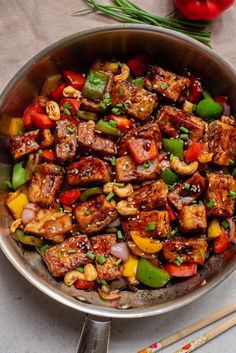 a pan filled with meat and vegetables on top of a table next to chopsticks