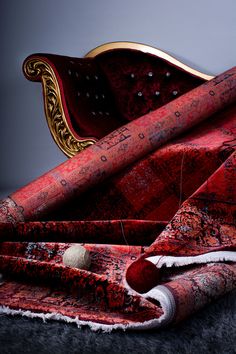 an ornate red chair with gold trimmings sits on a gray carpeted floor