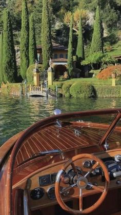 the steering wheel and dashboard of a boat on water with lots of trees in the background