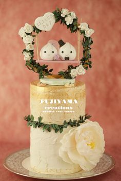 a wedding cake with two birds on top and flowers in the middle, sitting on a plate