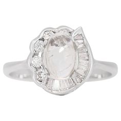 This enchanting ring, masterfully crafted in 14K white gold, is a stunning amalgamation of ethereal beauty and sparkling elegance. The centerpiece is a captivating moonstone, weighing 0.60 carats, renowned for its mesmerizing play of light and mystical allure. Surrounding this mystical stone are 5 round brilliant natural diamonds, collectively weighing 0.10 carats, and 12 taper-shaped diamonds totaling 0.12 carats. These diamonds, all graded H in color, exude a warm, near-colorless shimmer. Thei Diamond Color Grade, Ethereal Beauty, Moon Stone, Diamond Stone, Solitaire Ring, Round Brilliant, Diamond Rings, Colored Diamonds, Moonstone