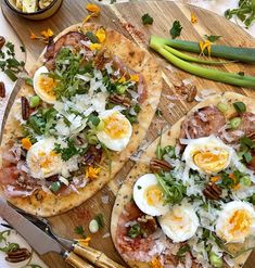 two pizzas with an assortment of toppings are on a cutting board next to a knife