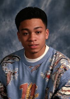 a young man in a blue sweater posing for a photo with his hands on his hips