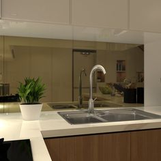 a modern kitchen with white counter tops and wooden cabinets, along with a plant in the center