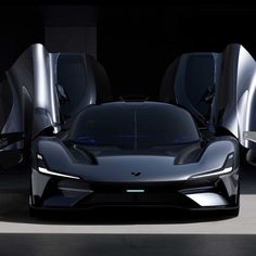 an electric sports car with its doors open in a dark room next to other cars