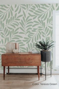 a living room with green wallpaper and a plant on the table in front of it