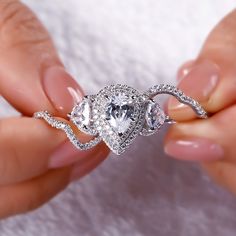 two hands holding an engagement ring with three pear shaped diamonds