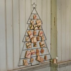 a small christmas tree made out of wrapped presents sitting on top of a shelf next to a candle