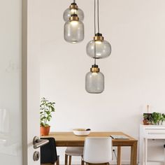 three lights hanging over a table in a room with white walls and wooden flooring