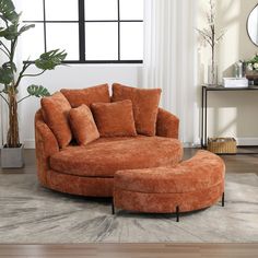 a living room with an orange round couch and ottoman in front of a large window