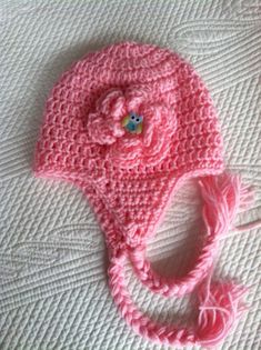 a pink crocheted hat with a flower on it sitting on top of a bed