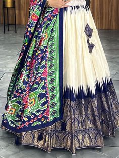 Elevate your ethnic wear collection with this stunning off-white & navy blue patola printed dola silk lehenga choli. Crafted with exquisite detailing, this ensemble exudes elegance and charm, perfect for any festive occasion. The off-white and navy blue color combination adds a touch of sophistication, while the patola and paithni printed work, foil work, and crush work elevate the traditional look to a whole new level.
The key features of this lehenga choli set include the intricately desig Ikat Print Lehenga For Wedding And Navratri, Unstitched White Lehenga With Motifs, White Lehenga With Motifs Unstitched, White Ikat Print Dupatta For Navratri, Traditional Ikat Print Lehenga For Navratri, White Art Silk Lehenga With Motifs, Anarkali Style Festive Lehenga With Ikat Print, White Ikat Print Traditional Wear For Diwali, Anarkali Style Lehenga With Ikat Print For Diwali