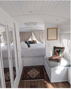 the inside of a camper with white walls and wood flooring