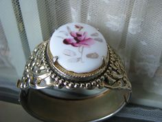 A beautifully ornate gold washed floral filigree painted glass rose cameo hinged bangle bracelet. The cameo measures 1 5/8'' x almost 1 1/4''. The bracelet measures 1 7/8'' at the widest. Also measures 2 1/2'' x 2 1/8'' across, and 7 5/8'' along the inside. In very good condition with subtle subduing of the gold. revealing the cool shiny silver underneath. Victorian Rose Gold Bracelets Gift, Victorian Bangle Bracelets For Wedding, Victorian Rose Gold Bracelets As Gift, Victorian Bangle Bracelet For Wedding, Wedding Filigree Adjustable Bracelets, Adjustable Filigree Bracelets For Wedding, Antique White Bracelet Jewelry, Silver Cameo Bracelet For Gifts, White Antique Bracelet Jewelry