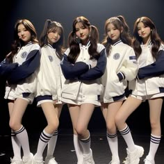 four girls in white and blue uniforms posing for the camera