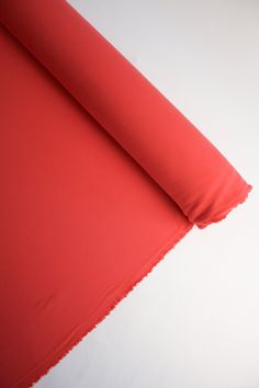 a red piece of cloth is laying on top of a white surface with the fabric pulled back