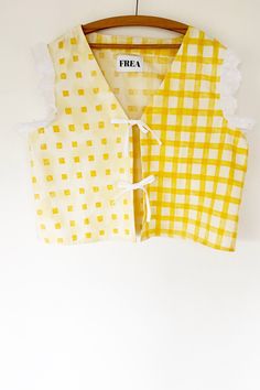 two yellow and white shirts hanging on a wooden hanger