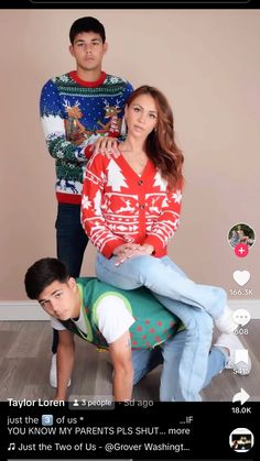 two people standing next to each other in front of a wall with christmas sweaters on