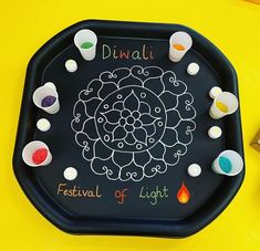 a black tray that has different colored paints on it and the words diwali written in white