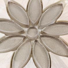 a flower shaped object on top of a white table with grey and beige designs in the center