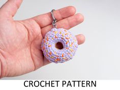 a hand holding a crochet donut keychain