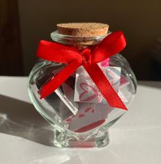 a glass jar filled with candy and wrapped in red ribbon