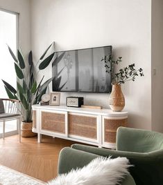 a flat screen tv sitting on top of a white entertainment center next to a window