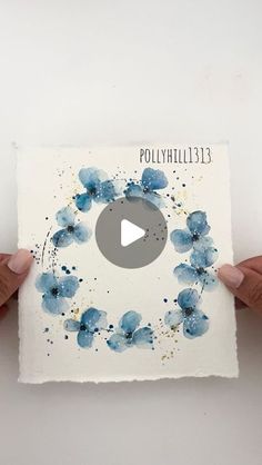 two hands holding up a piece of paper with watercolor flowers on it and the words polyhyhillite 13