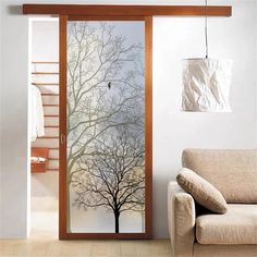 a living room with a couch, chair and glass door that has trees on it