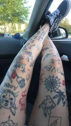 someone with tattoos on their legs sitting in a car