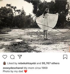 an old photo of a woman holding a kite in the middle of a dirt field