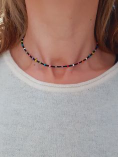 a woman wearing a necklace with multicolored beads and a black beaded cord